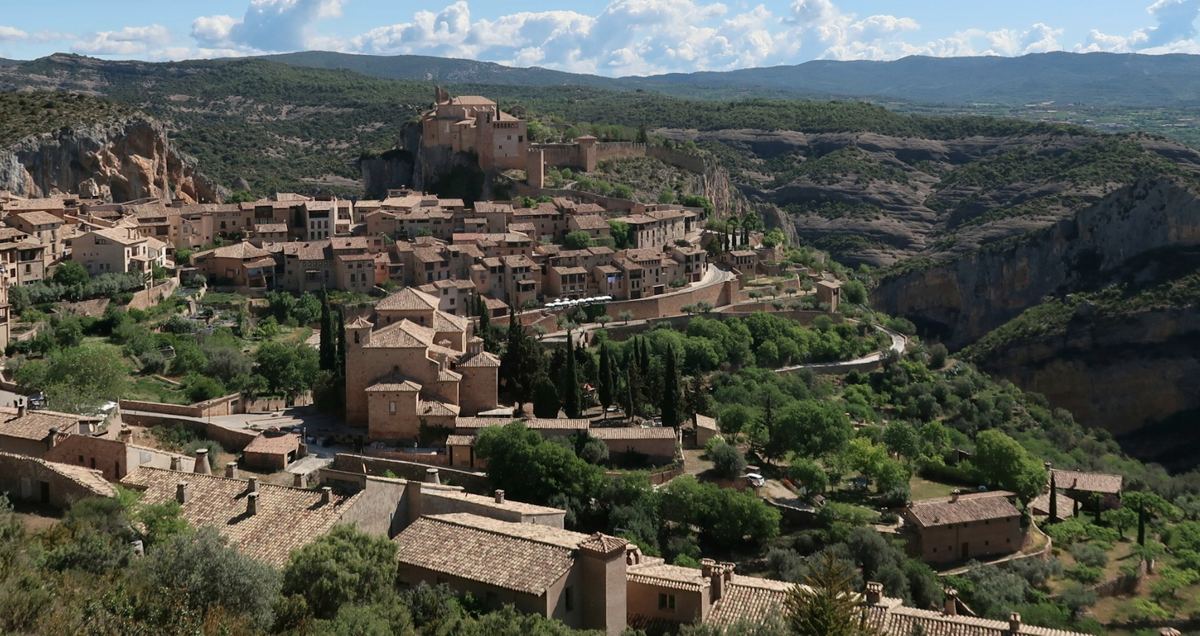 A village of stone houses on a rise above a green valley.